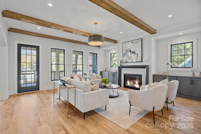 living room featuring a fireplace, beamed ceiling, and light hardwood / wood-style floors