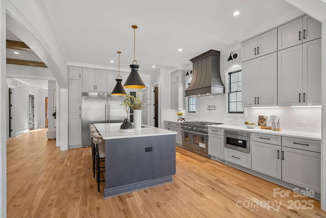 kitchen featuring premium appliances, gray cabinets, a kitchen island, and custom exhaust hood