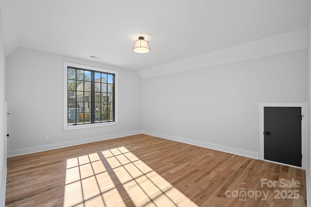 unfurnished room with lofted ceiling and wood-type flooring