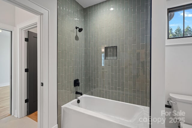 bathroom featuring toilet, tiled shower / bath combo, and hardwood / wood-style floors