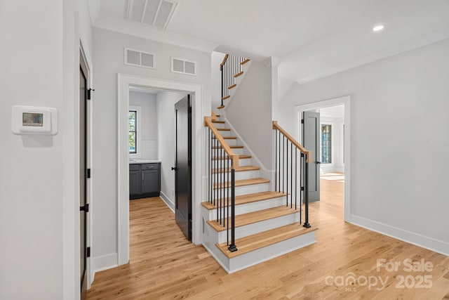 staircase featuring crown molding and hardwood / wood-style flooring