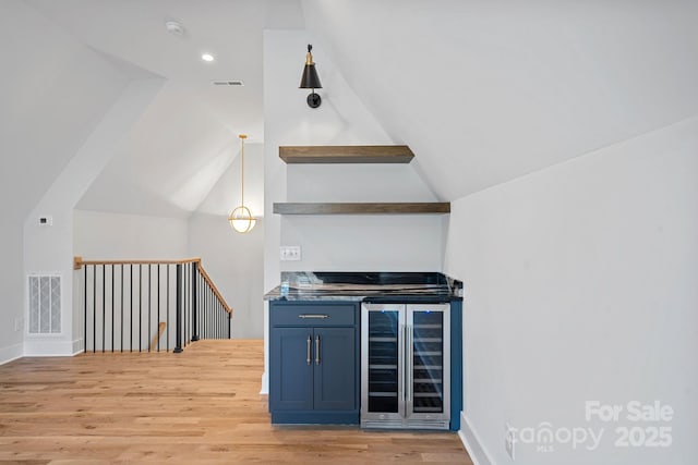 bar featuring beverage cooler, blue cabinets, hanging light fixtures, vaulted ceiling, and light hardwood / wood-style flooring