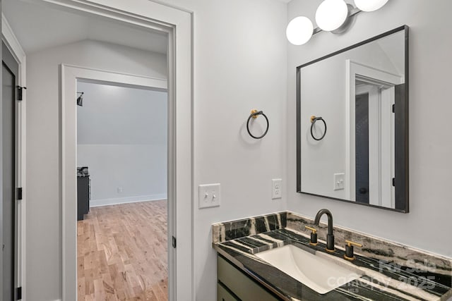 bathroom with lofted ceiling, vanity, and hardwood / wood-style floors