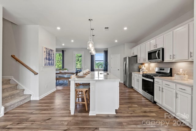 kitchen with decorative backsplash, appliances with stainless steel finishes, white cabinetry, and a kitchen island