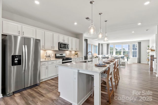 kitchen with sink, white cabinetry, a kitchen island with sink, and appliances with stainless steel finishes