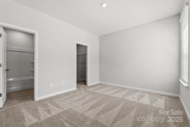 unfurnished bedroom featuring a walk in closet, a closet, and carpet floors