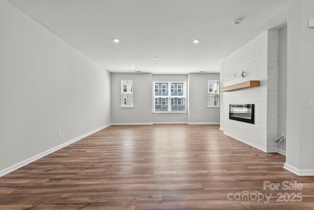 unfurnished living room with dark wood-type flooring and a fireplace