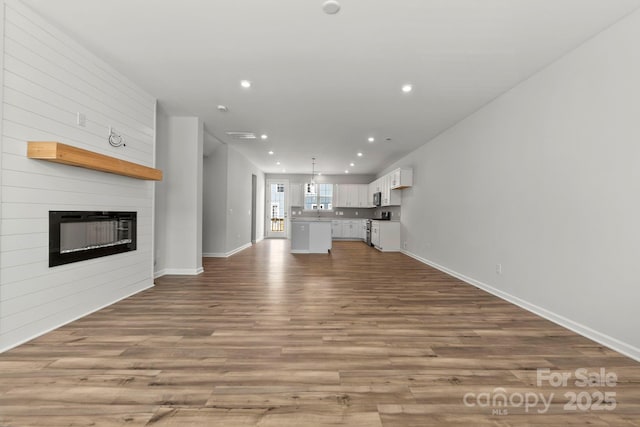 unfurnished living room featuring a large fireplace and light hardwood / wood-style flooring