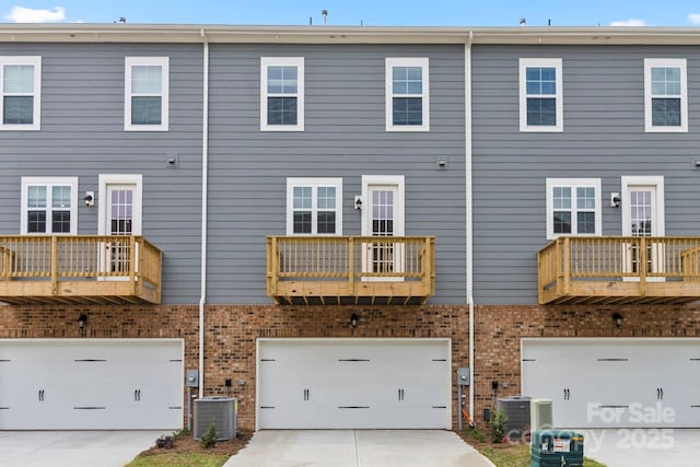 rear view of property featuring central AC unit and a garage