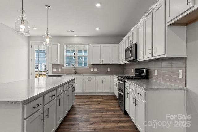 kitchen featuring stainless steel appliances, decorative light fixtures, white cabinetry, light stone counters, and dark hardwood / wood-style flooring