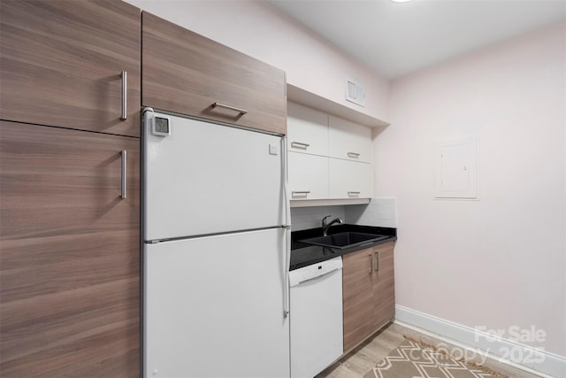 kitchen with backsplash, white appliances, sink, light hardwood / wood-style flooring, and white cabinetry