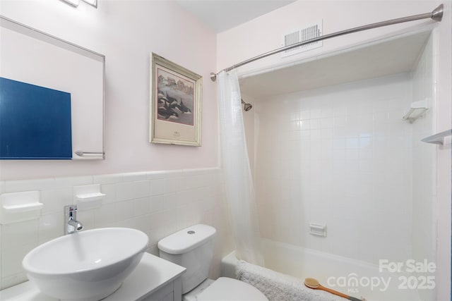 full bathroom with sink, shower / bath combination with curtain, tile walls, and toilet