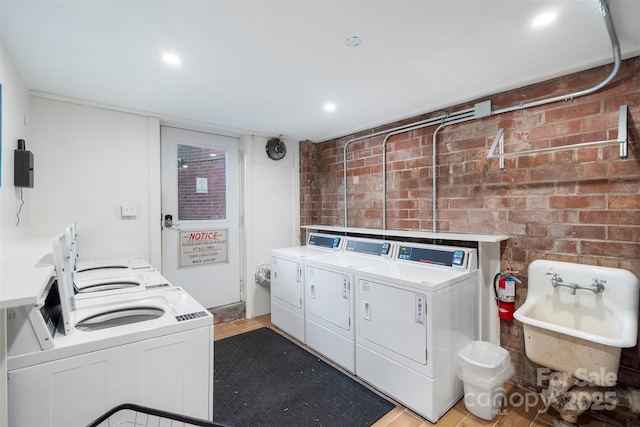 laundry room with brick wall and washing machine and clothes dryer