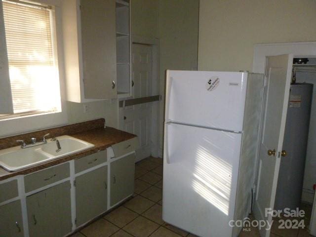 kitchen featuring white cabinets, sink, white fridge, and light tile patterned floors