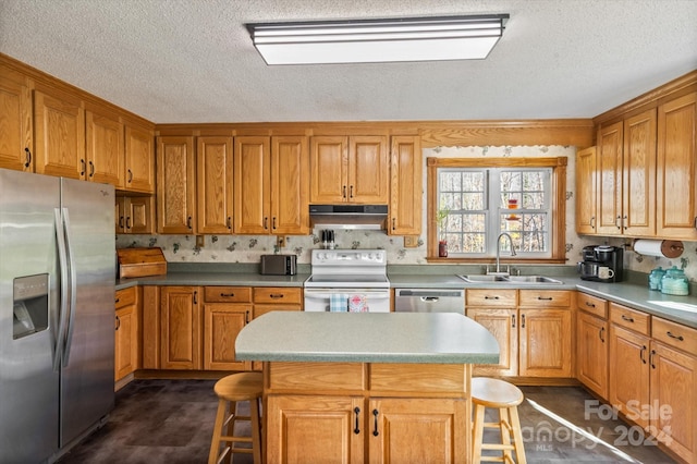 kitchen with a kitchen bar, appliances with stainless steel finishes, a kitchen island, and sink