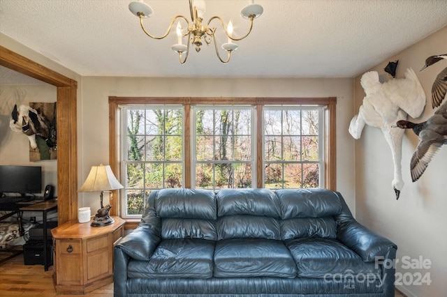 living room with hardwood / wood-style floors, a textured ceiling, plenty of natural light, and a notable chandelier