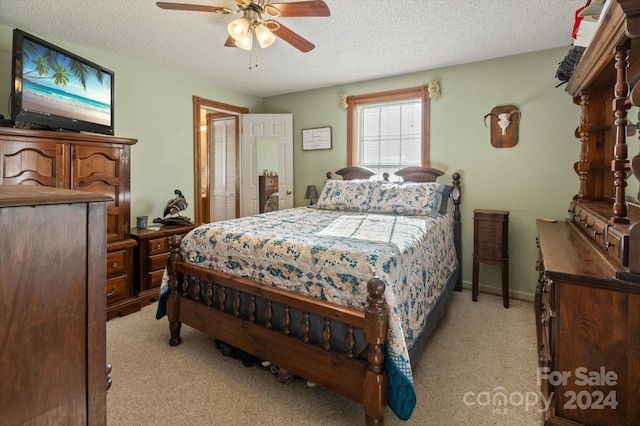 bedroom featuring ceiling fan, a textured ceiling, light carpet, and a closet