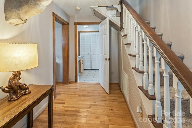 hallway with a textured ceiling and light wood-type flooring