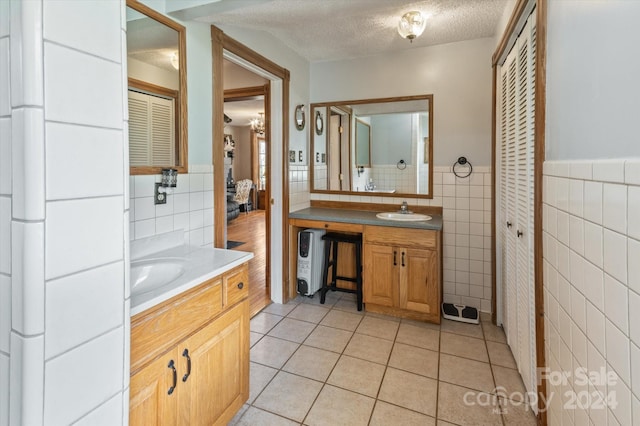 bathroom featuring tile patterned floors, vanity, tile walls, and a textured ceiling