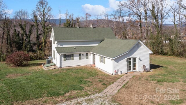 back of house featuring a mountain view and a yard