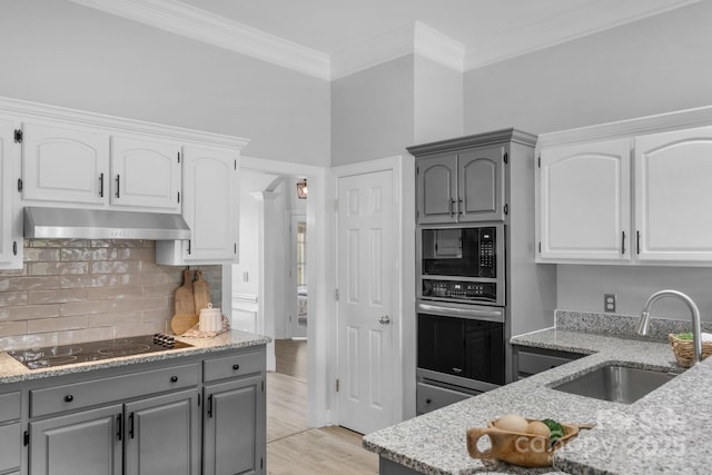 kitchen with sink, light stone counters, white cabinets, black electric cooktop, and stainless steel oven