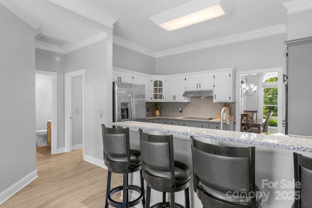 kitchen with light hardwood / wood-style flooring, white cabinetry, light stone counters, tasteful backsplash, and stainless steel fridge with ice dispenser