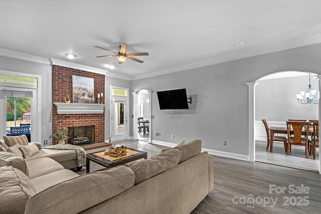 living room featuring decorative columns, ornamental molding, dark hardwood / wood-style floors, and a fireplace