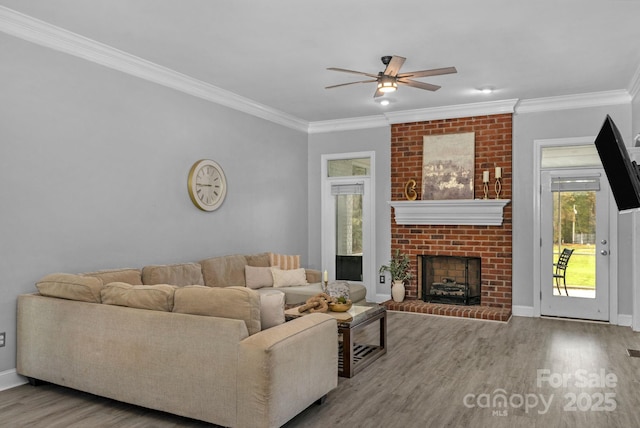 living room featuring crown molding, ceiling fan, light hardwood / wood-style floors, and a brick fireplace