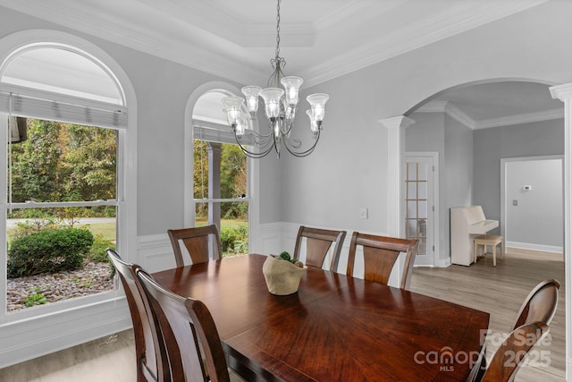 dining room with decorative columns, ornamental molding, a chandelier, and light wood-type flooring