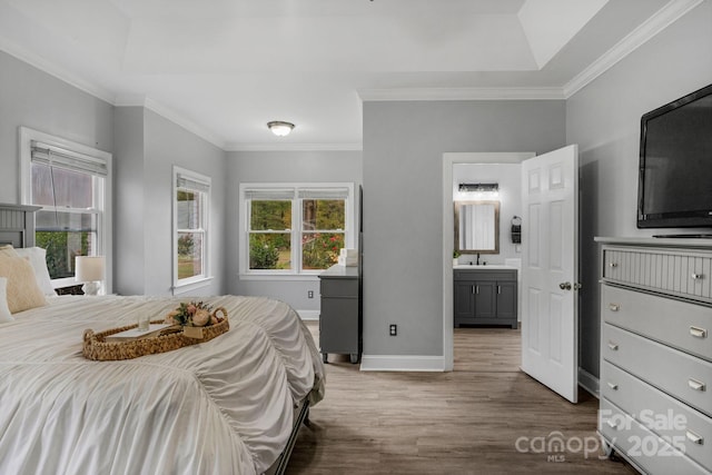 bedroom featuring ensuite bathroom, dark hardwood / wood-style floors, sink, a raised ceiling, and crown molding