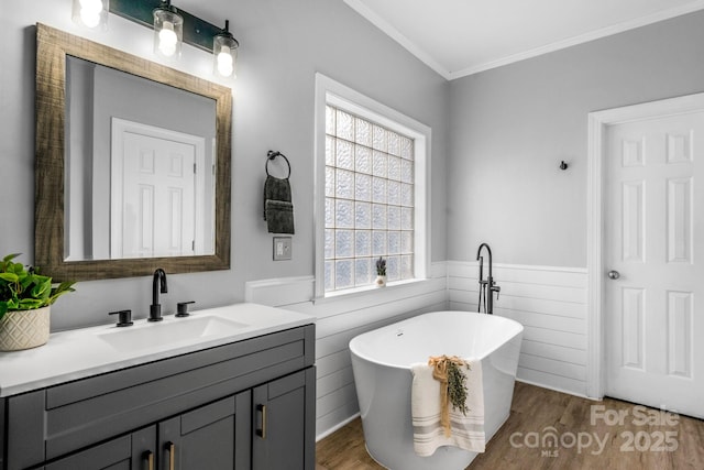 bathroom featuring a bathing tub, ornamental molding, hardwood / wood-style floors, and vanity