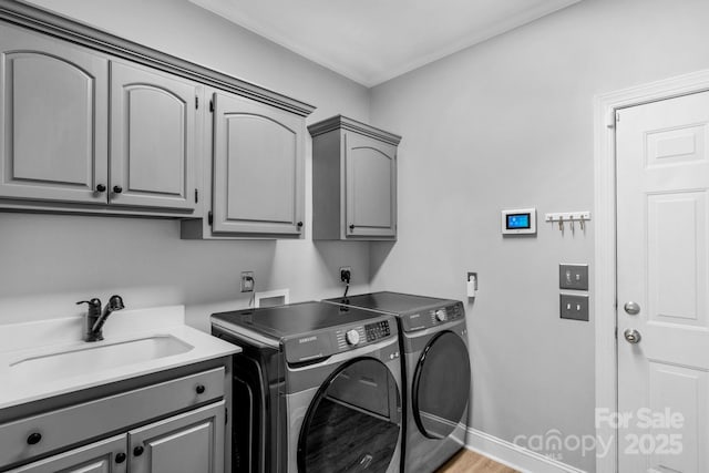 laundry area featuring cabinets, sink, washer and clothes dryer, and light wood-type flooring