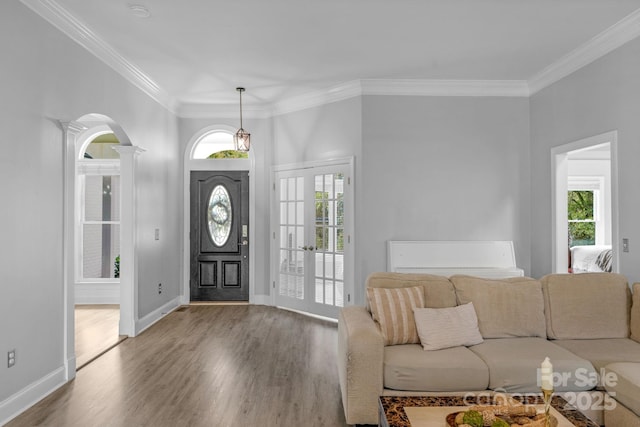 entryway with crown molding, wood-type flooring, and ornate columns