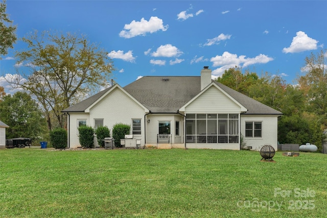 rear view of property featuring a yard, an outdoor fire pit, and a sunroom