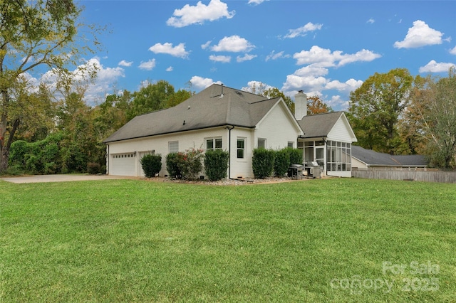 rear view of property with a garage, a sunroom, and a lawn