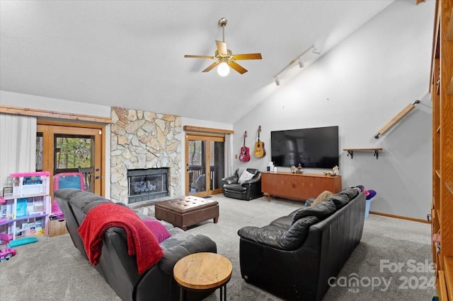 carpeted living room featuring a fireplace, ceiling fan, track lighting, and vaulted ceiling