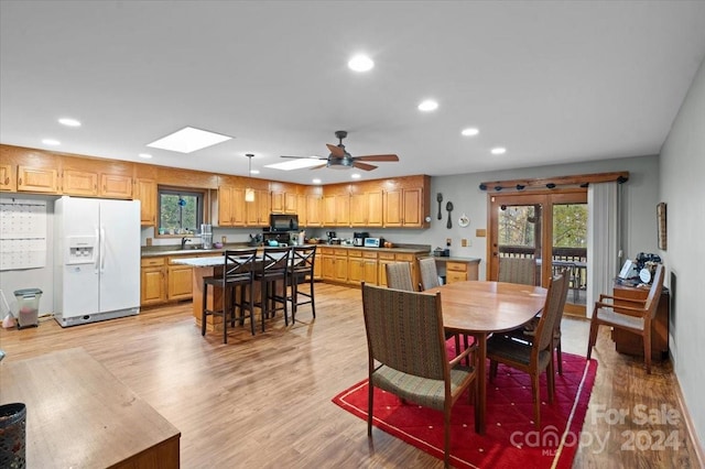 dining space featuring light hardwood / wood-style floors, ceiling fan, a skylight, and sink