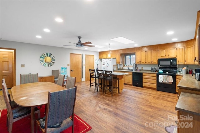 dining room featuring light hardwood / wood-style flooring, ceiling fan, a skylight, and sink