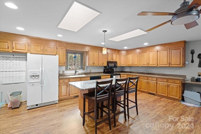 kitchen featuring a center island, sink, black appliances, and light hardwood / wood-style flooring