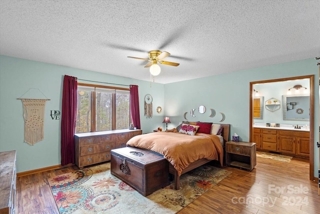 bedroom with light hardwood / wood-style floors, sink, ensuite bathroom, ceiling fan, and a textured ceiling