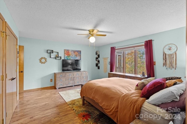 bedroom with light hardwood / wood-style floors, ceiling fan, and a textured ceiling