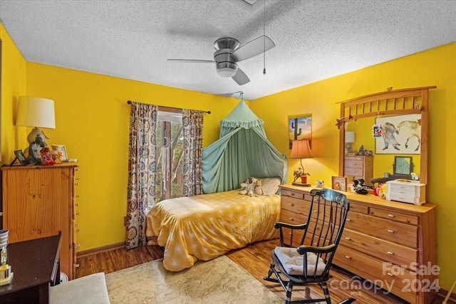 bedroom with a textured ceiling, hardwood / wood-style flooring, and ceiling fan