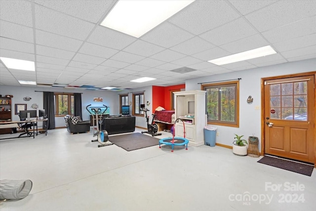 workout room featuring a drop ceiling, a healthy amount of sunlight, and concrete floors