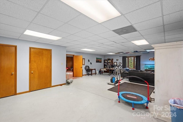 workout room featuring a paneled ceiling and concrete floors