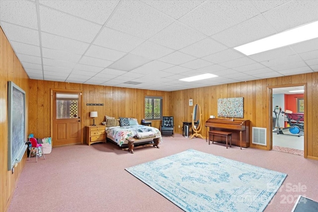 carpeted bedroom with a drop ceiling and wooden walls