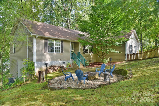 view of front of house featuring central air condition unit, a front yard, and a fire pit