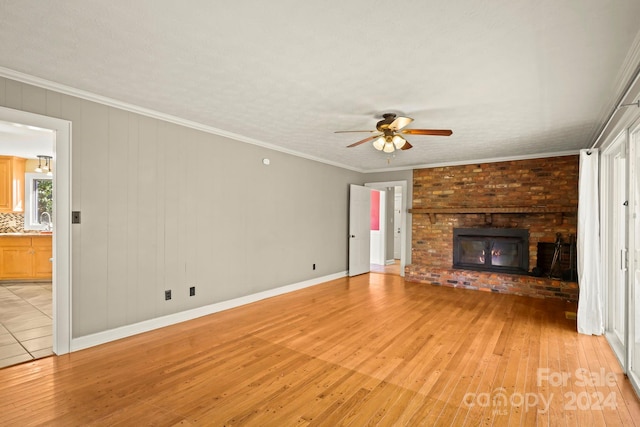 unfurnished living room with crown molding, light hardwood / wood-style flooring, a brick fireplace, and ceiling fan