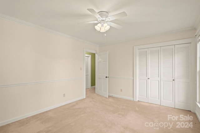 unfurnished bedroom with crown molding, a closet, light colored carpet, and ceiling fan