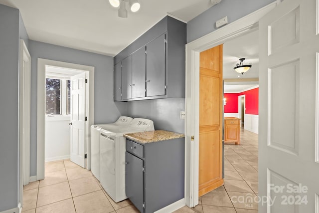 washroom featuring light tile patterned flooring, washing machine and dryer, and cabinets