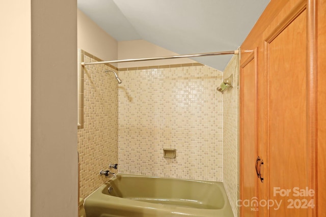 bathroom featuring tiled shower / bath and lofted ceiling